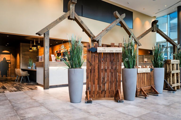 Holzbetonte Lobby, Grünpflanzen, moderne Rezeption - ideales Familienhotel buchen.