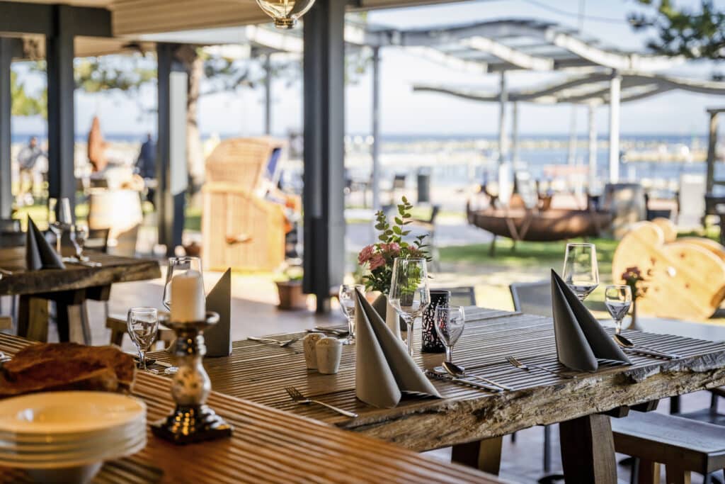 Am Meer gedeckter Holztisch, schattige, familienfreundliche Küche.