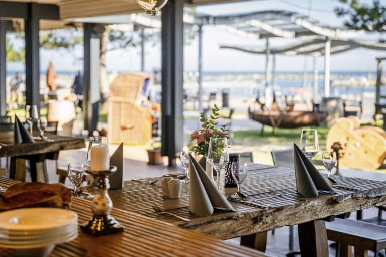 Am Meer gedeckter Holztisch, schattige, familienfreundliche Küche.