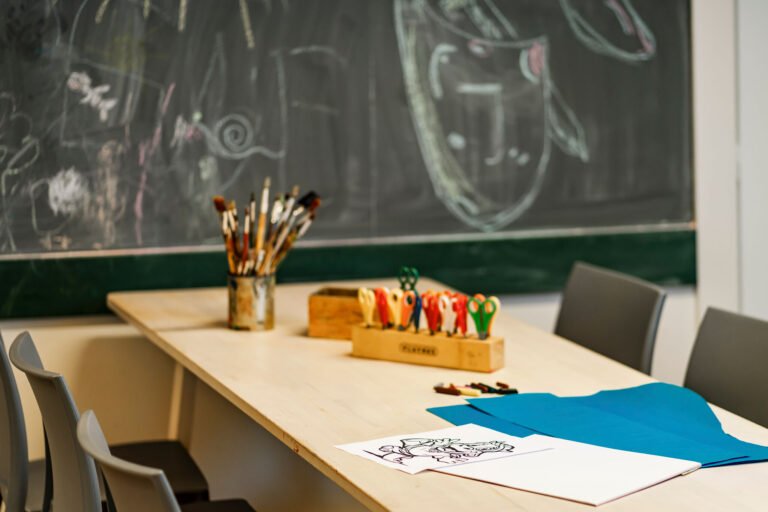 Kunsttisch mit Material, Stühlen und einem Hintergrund aus Kreide.