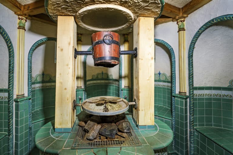 Steinschale mit Steinen auf Sockel, umgeben von dekorativen Fliesen.