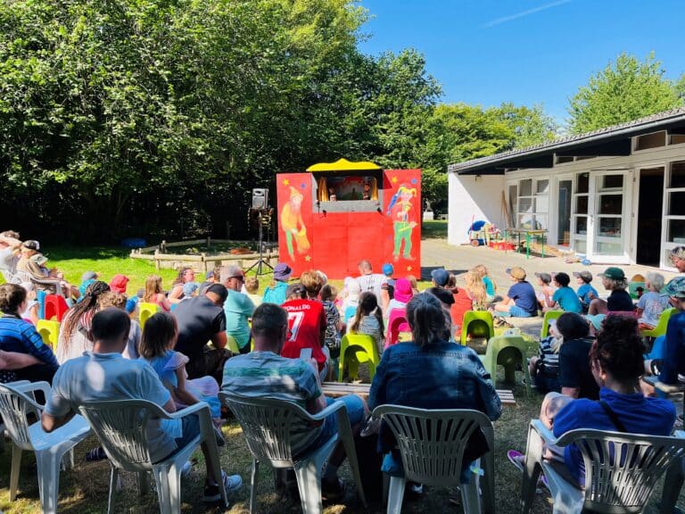 An einem sonnigen Tag wird draußen ein Puppentheater aufgeführt.