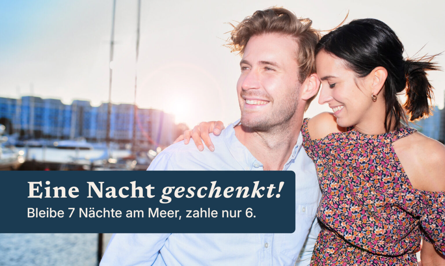 Lächelndes Paar am Yachthafen; Angebot Nacht_kostenlose_Woche_ostsee_DE in Deutsch.