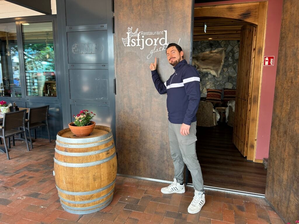 Restaurant-Isfjord_chris-savaj zeigt auf das Schild am Eingang.