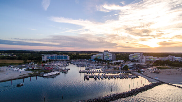 Sunset_marina.jpg: Yachthafen, Yachten, städtische Gebäude, Sandstrand, Sonnenuntergangsglühen.