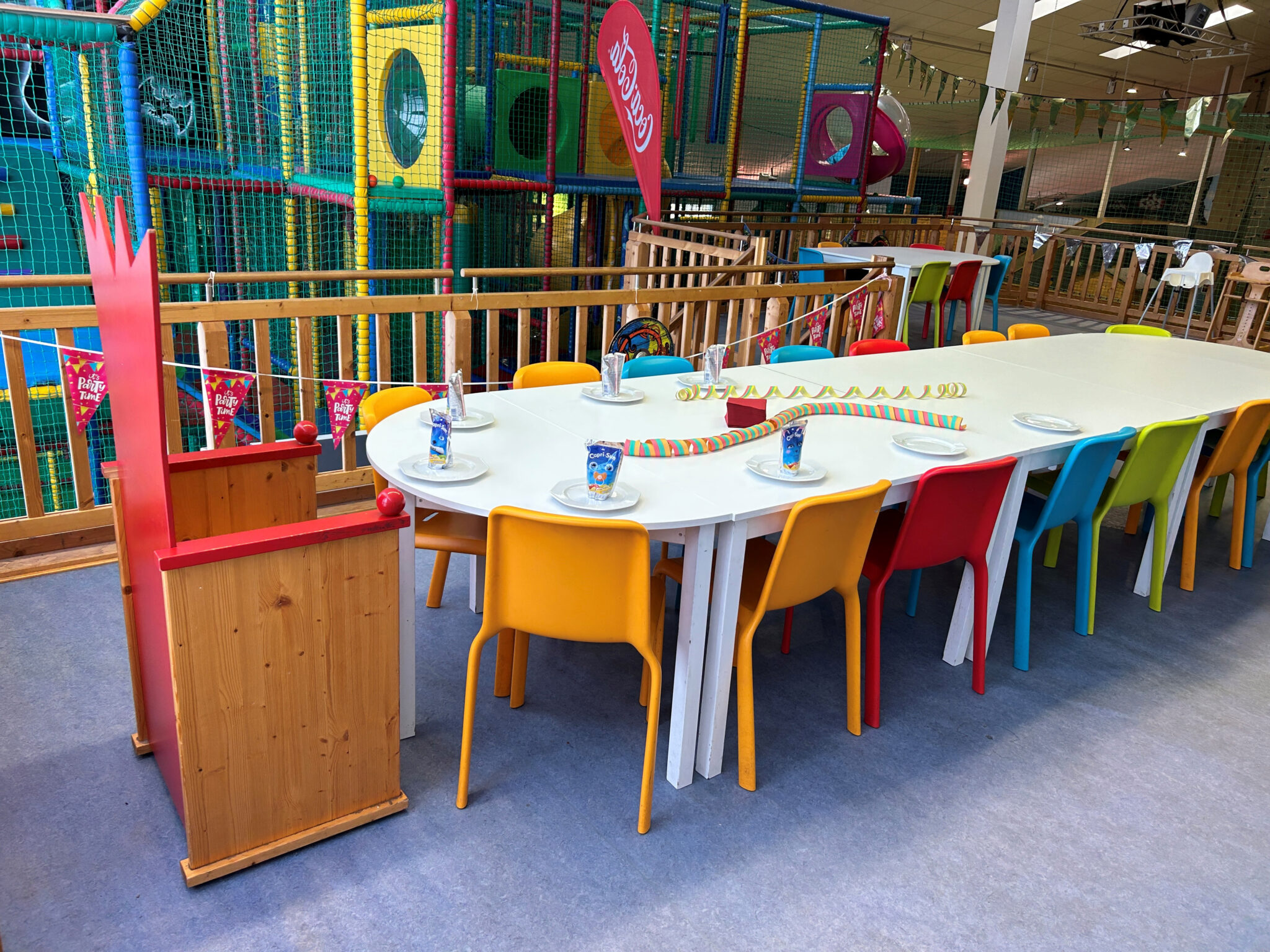 Geburtstag_im_urlaub_feiern: Kinderpartytisch, Dekoration, Spielecke, bunte Stühle.