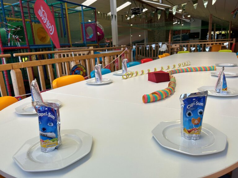 Geburtstag-im-urlaub-feiern: Kinderparty-Tisch, Capri-Sonne, Softplay-Bereich.