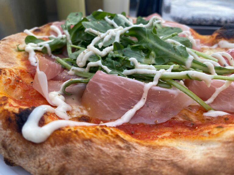 Echte-feuchte-originale-birgit-foerster: Pizza mit Prosciutto, Rucola, weißer Sauce und verkohlter Kruste.