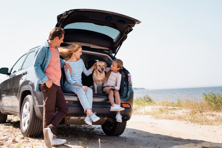 StrandUrlaub_FamilienResort: Familie und Hund entspannen sich im SUV am Strand.