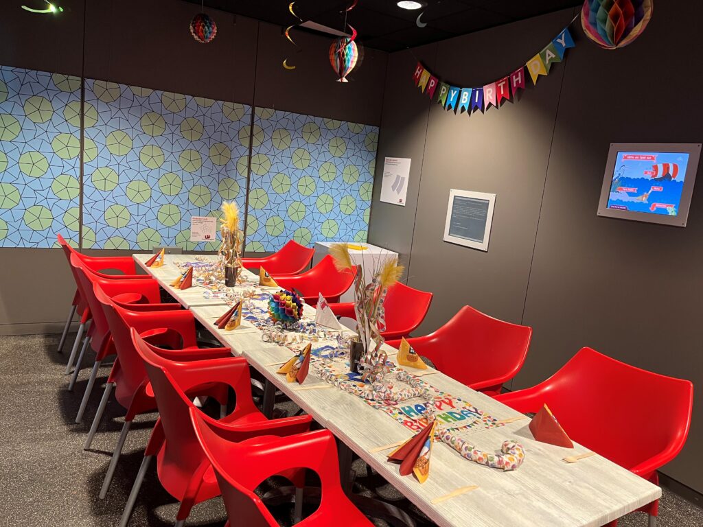 Party-table-geburtstag.jpg zeigt festlichen Tisch, rote Stühle, Fahnen.