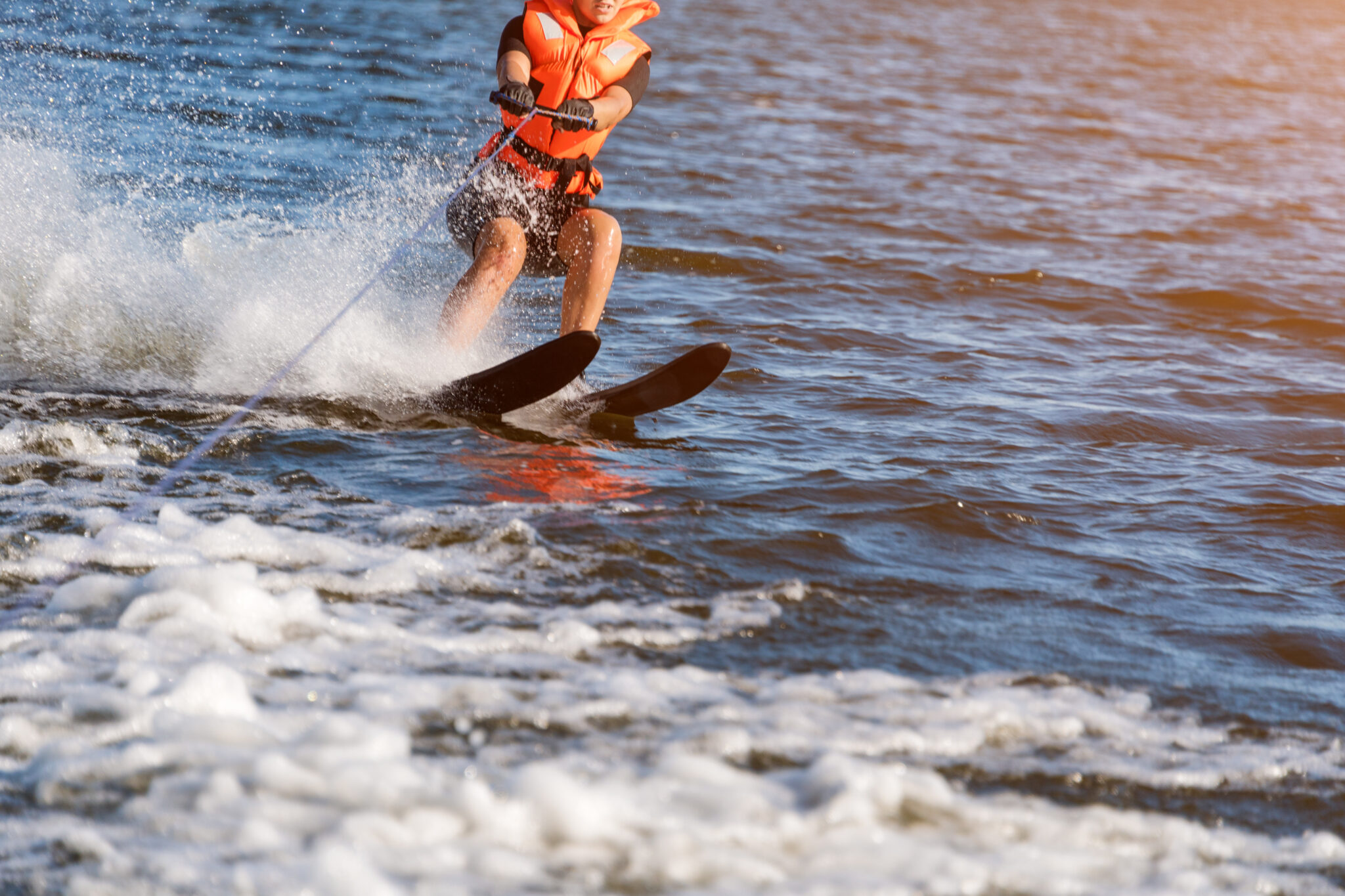 Waterski_baltic_resort.jpg: Person water skiing, lifejacket on, splashing at Baltic resort.