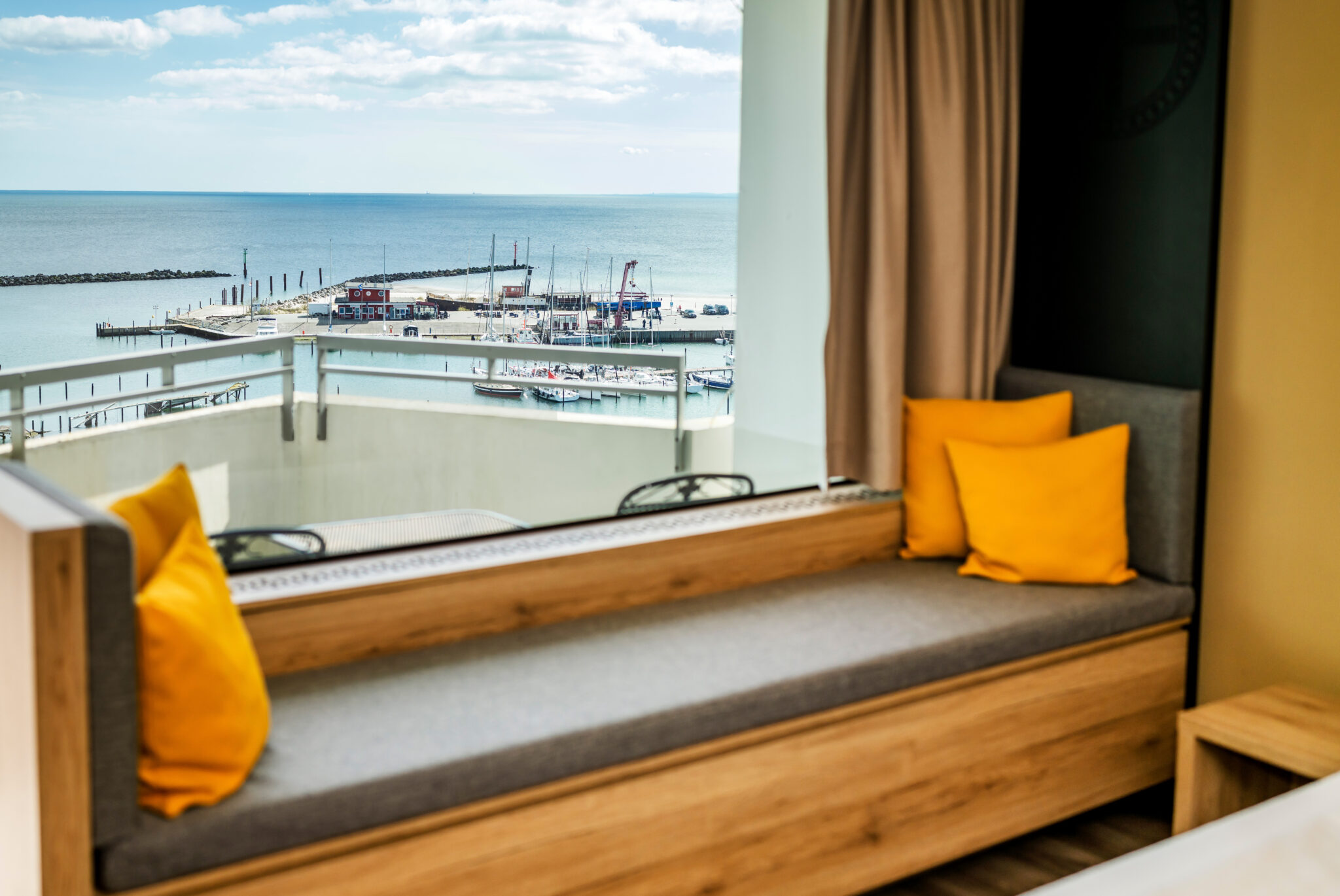 Superiorzimmer mit Panoramabank und roten und gelben Kissen sowie Meerblick im Hotel Midgard, Damp Ostsee Resort