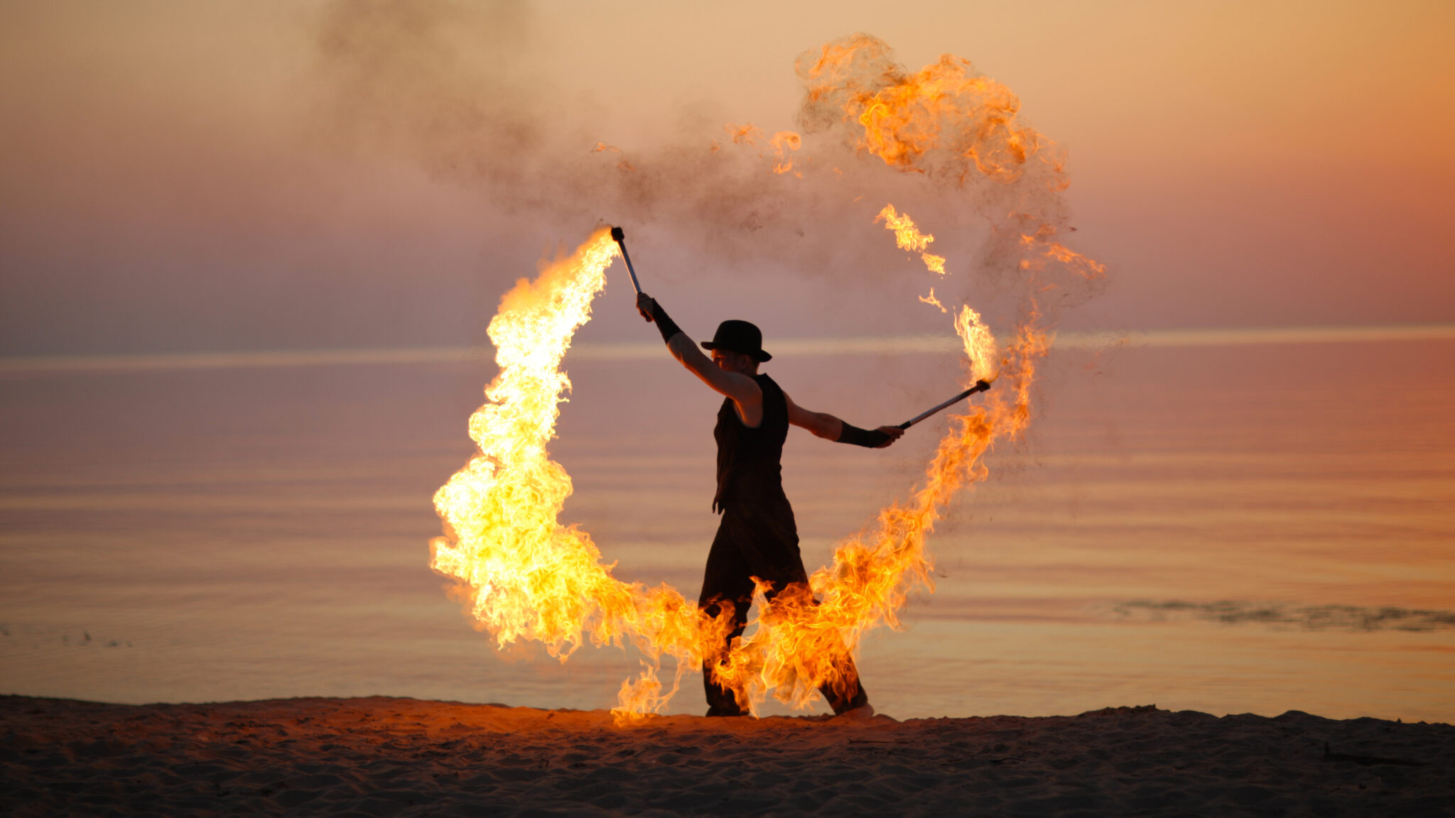 Ostsee_performance.jpg: Flammender Stabbogen am Strand bei strahlendem Sonnenuntergang.