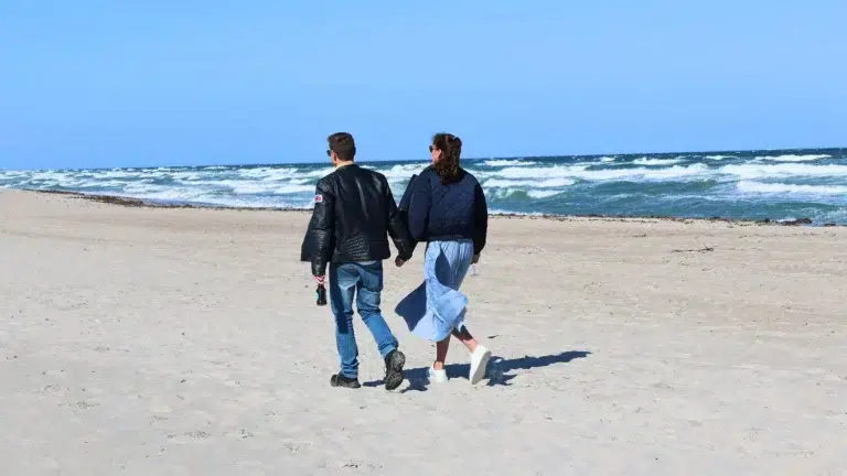 Ein Paar spaziert am Strand des Ostsee Resorts Damp entlang – ein erholsamer Urlaub.