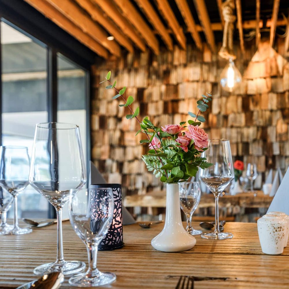 Gedeckter Tisch mit Weingläsern, rosa Blumen und Kerzen - romantisch.