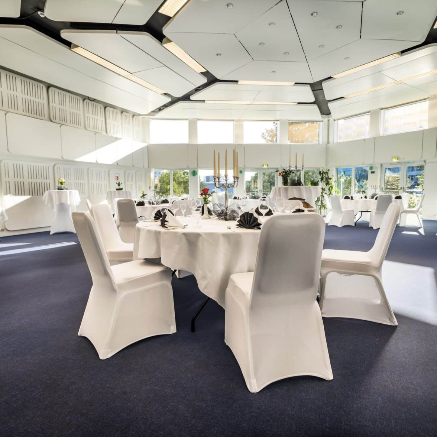 Heller Bankettsaal mit modernem Dekor, Sonnenlicht und eleganten Tischen.