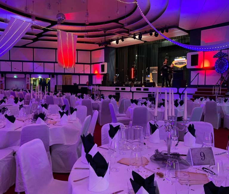 Familienhotel_silvester.jpg: Eleganter Festsaal, festliche Beleuchtung, Gäste feiern auf der Bühne.