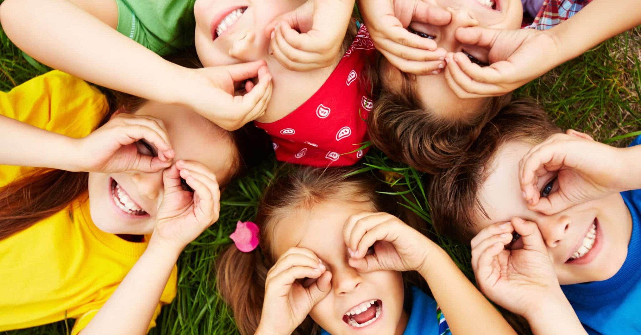 Sechs fröhliche Kinder machen ein Handfernglas und lächeln im Kreis.