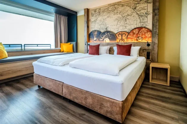 Gemütliches Hotelzimmer: großes Bett, Landkarten-Wandbild, Nähe Ostseebad.